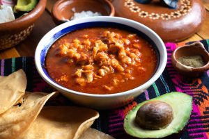Plato de pozole rojo con aguacate