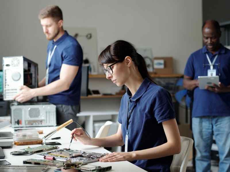 Jóvenes técnicos reparando computadoras en un laboratorio moderno, ejemplo de formación técnica 4.0 orientada al empleo.