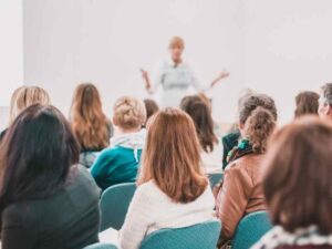 Grupo de jóvenes asistiendo a una conferencia mientras una instructora expone, ilustrando la conexión entre educación técnica 4.0 y el mercado laboral.