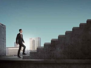 Persona subiendo escalera como símbolo de crecimiento profesional en el entorno laboral.