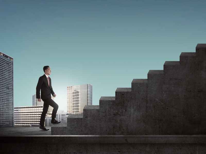 Persona subiendo escalera como símbolo de crecimiento profesional en el entorno laboral.