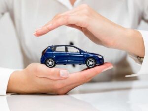 manos cubriendo un auto de juguete simulando el seguro de auto