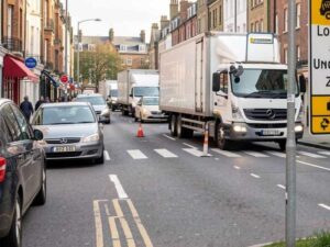 Fotografía de una calle con señalización clara de "Zona de Carga y Descarga", con un camión de entregas operando de forma ordenada sin obstruir el tráfico. Tono de eficiencia logística.